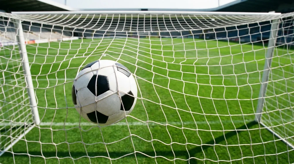 Balón de fútbol dentro de la red de una portería en un estadio de fútbol profesional con césped verde